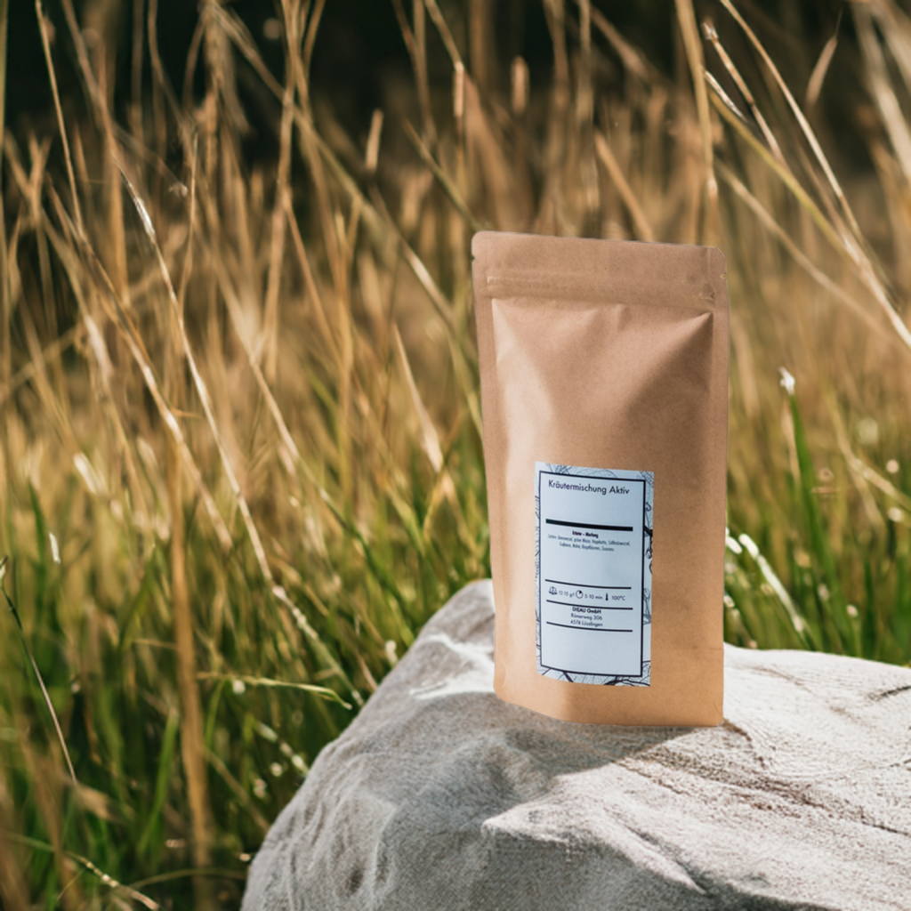 Eine braune Verpackung mit der Aufschrift Kräutermischung Aktiv steht auf einem großen, hellen Stein inmitten eines Feldes mit hohen, goldenen Gräsern. Die Naturkulisse hebt das Produkt hervor und vermittelt ein Gefühl von Natürlichkeit und Frische.